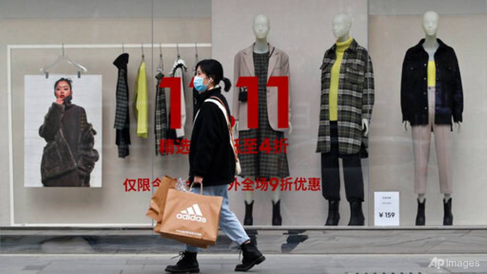 쇼핑을 마친 여성이 중국 광군제(The Single's DaY) 세일을 하는 패션 부띠끄 매장 앞을 지나고 있다, china singles day, Photo by AP Andy Wong
